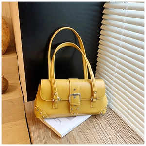 Nahaufnahme gelbe Lederhandtasche mit silbernen Nieten und Schnallen auf Holztisch