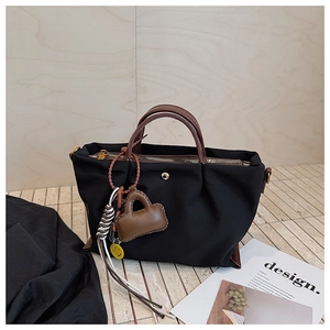 Vue détaillée du sac cabas en nylon noir avec anses en cuir et mini charm de sac