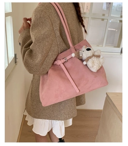 Detailed view of pink suede tote bag with a cute bear charm and slim shoulder straps