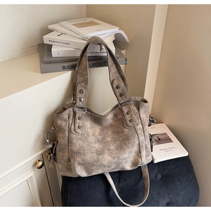 Sac cabas vintage abricot avec texture cuir et rivets argentés posé sur un tabouret