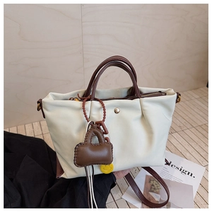 Détail du sac plissé crème avec poignées marron, boucle dorée et pendentifs mignons