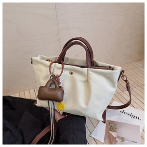 Détail du sac fourre-tout plissé beige avec poignées marron et pendentif décoratif