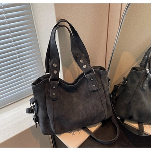 Détail d'un sac cabas en daim gris foncé avec texture vintage et rivets argentés