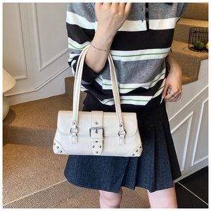 Schicke cremeweiße Schultertasche aus Kunstleder mit Schnalle und Nieten am Modell