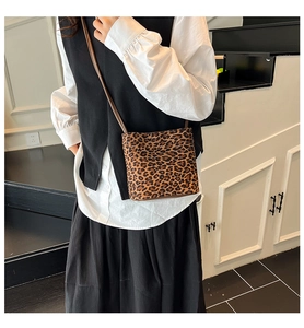 Detail view of a leopard print bucket bag with brown strap on a model outfit