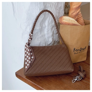 Close-up of brown woven leather bag featuring a silk scarf detail and metal hooks