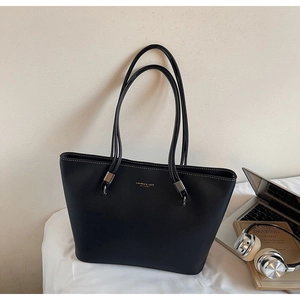 Close-up of black leather tote bag featuring white contrast stitching and silver hardware