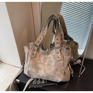 Détails d'un sac cabas vintage gris avec des rivets argentés et une texture mate