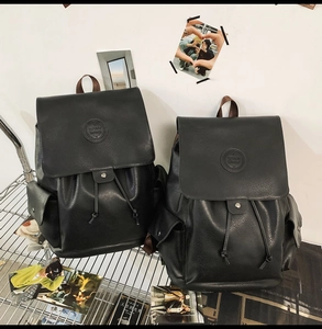Detail of vintage black PU leather backpack with drawstring closure and brown web handle