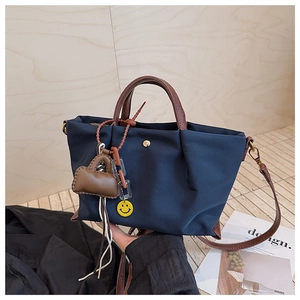 Détail du sac dumpling en nylon bleu marine avec plis et anses en cuir marron