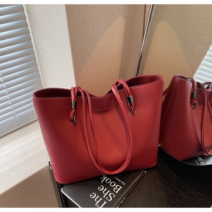 Detail of dark red lychee grain leather tote bag with contrast stitching and gold logo