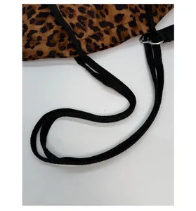 Détail du sac léopard montrant la bandoulière tressée noire et l'anneau en métal poli