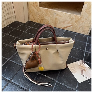Détail du sac cabas plissé beige avec poignées en cuir marron et pendentif smiley