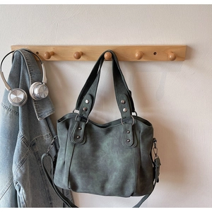 Vue détaillée du sac cabas vert gris avec anneaux argentés sur un crochet en bois