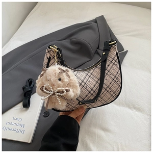 Detail of beige plaid crescent bag with black leather trim and plush rabbit charm