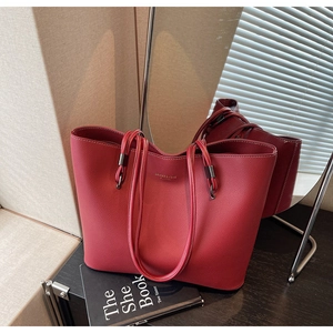 Detail of red pebbled leather tote bag with gold logo and dual shoulder straps