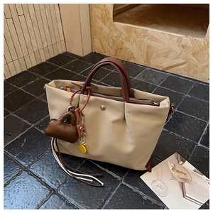 Détail du sac beige avec poignée à motif serpent et accessoire de mini sac suspendu