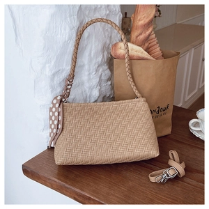 Close-up of woven shoulder bag texture with polka dot silk scarf detail and extra strap