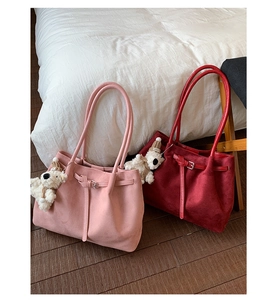 Detail of suede tote bags in pink and wine red featuring a plush bear keychain accessory
