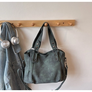 Détail du sac seau vintage vert foncé avec rivets métalliques et texture en cuir matifié