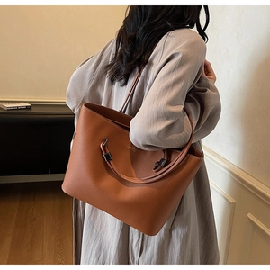 Detail of caramel leather tote bag with gold logo and signature metallic ring buckle