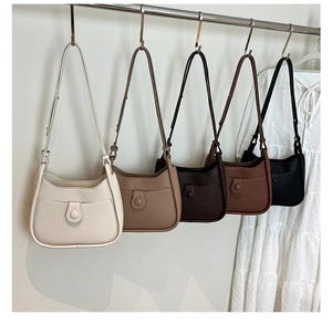 Group display of five colorful half-moon shoulder bags hanging on a rack with lace dress