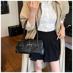 Vista lateral del bolso de hombro punk negro con tachuelas y hebilla en la modelo