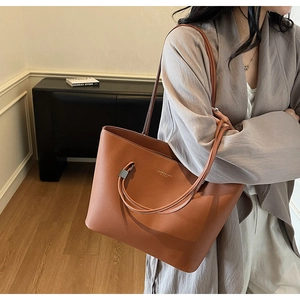 Close-up of brown faux leather tote bag showing lychee grain texture and gold logo