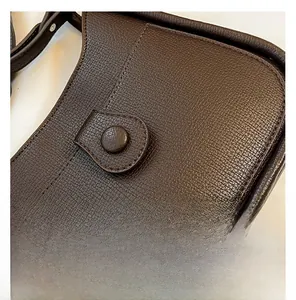 Detailed close-up of dark brown lychee-textured leather bag with neat stitching