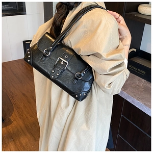 Detalle de bolso de hombro punk negro con tachuelas plateadas y hebillas metálicas en modelo