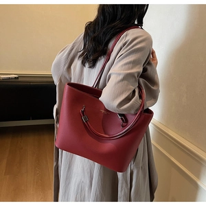 Close-up of red pebbled leather tote bag with gold logo and elegant shoulder strap