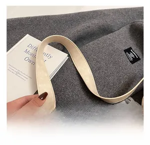 Detail shot of wide shoulder strap with silver buckle on beige faux leather tote bag