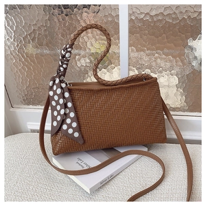 Close-up of brown woven shoulder bag with a polka dot silk scarf detail on a book