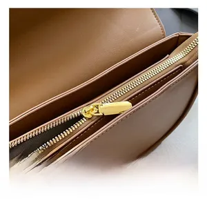 Detail of caramel brown leather saddle bag interior with golden zipper and multi-compartment
