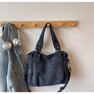 Détail du grand sac cabas gris en daim avec rivets, poignées et bandoulière amovible