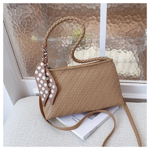 Detail of woven texture handbag with decorative silk scarf and adjustable shoulder strap