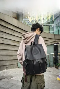 Model wearing a vintage black PU leather backpack with a large drawstring compartment and logo