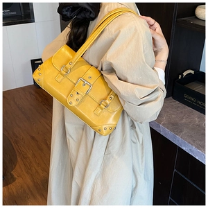 Detailansicht der gelben Lederschultertasche mit Nieten und Metallschnalle am Modell