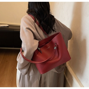 Detail view of the red lychee leather tote bag with elegant silver lettering on the surface