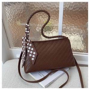 Close-up of dark brown woven texture handbag with polka dot silk scarf and strap