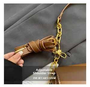 Detail of adjustable brown leather shoulder strap with elegant gold metal chain and hardware