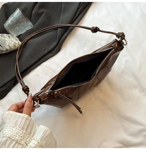 Detail view of large dark brown patent leather shoulder bag with wide open zipper and inner space