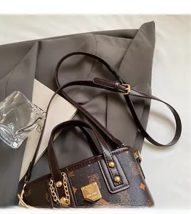 Detail of dark brown bucket bag with monogram print and golden metal chain accent