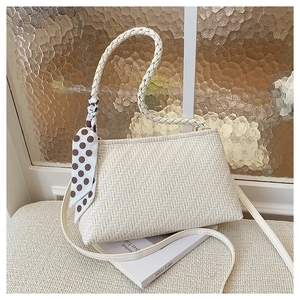 Detail of woven texture cream shoulder bag with brown polka dot silk scarf accessory