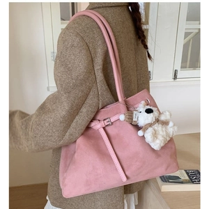 Pink suede tote bag with plush bear pendant shown on model in cozy interior setting