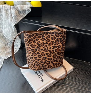 Close-up of retro bucket bag featuring leopard print fabric and slim brown leather strap