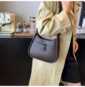 Detail view of deep brown litchi grain leather texture and front pocket on shoulder bag