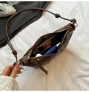 Interior view of brown patent leather crescent bag showing phone and lipstick storage