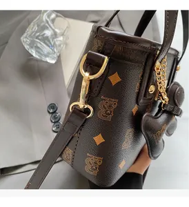 Close-up of golden metal hardware and dark brown bear pattern on leather bucket bag
