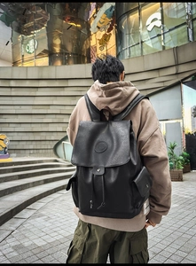 Outdoor shot of a large black vintage backpack with flap and drawstring closure